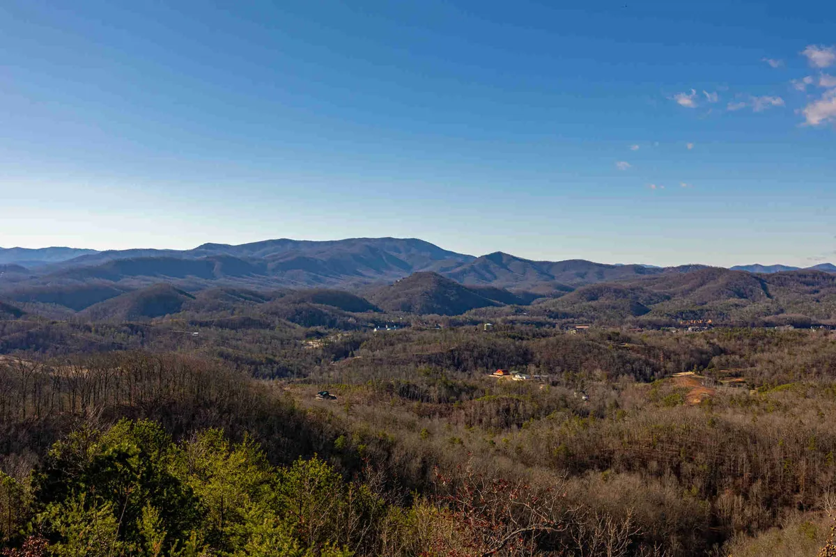 A wide, unobstructed view of distant mountains and rolling hills beneath a clear sky. The expansive scenery is peaceful and awe-inspiring, evoking the sense of adventure and exploration that couples might experience while visiting local attractions like Clingmans Dome or Cades Cove.