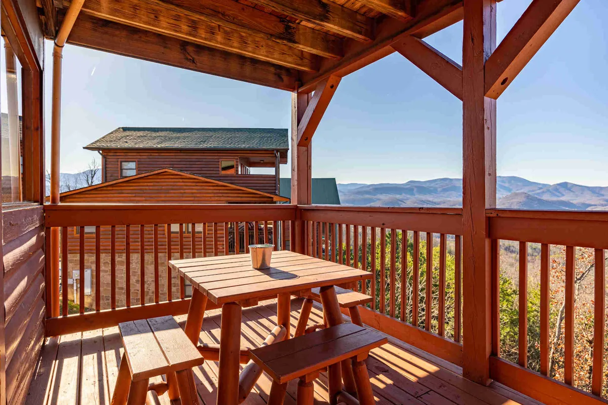 A tranquil outdoor dining area on the deck, with wooden patio furniture facing an unobstructed mountain view. A decorative potted plant adds a homely touch, reinforcing the sense of comfort and style.