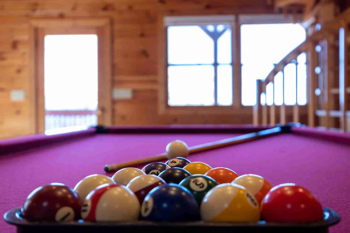 This interior image highlights a vibrant game room with a pool table, colorful billiard balls, and large windows letting in natural light. The setup encourages friendly competition and quality time, perfectly embodying the playful side of family retreats described in the section.