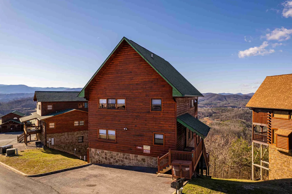 This exterior shot highlights a charming wooden cabin with a green roof nestled against a backdrop of majestic mountains. The porch and surrounding nature hint at opportunities for hiking and exploring nearby trails, resonating with the section's call for outdoor adventure.