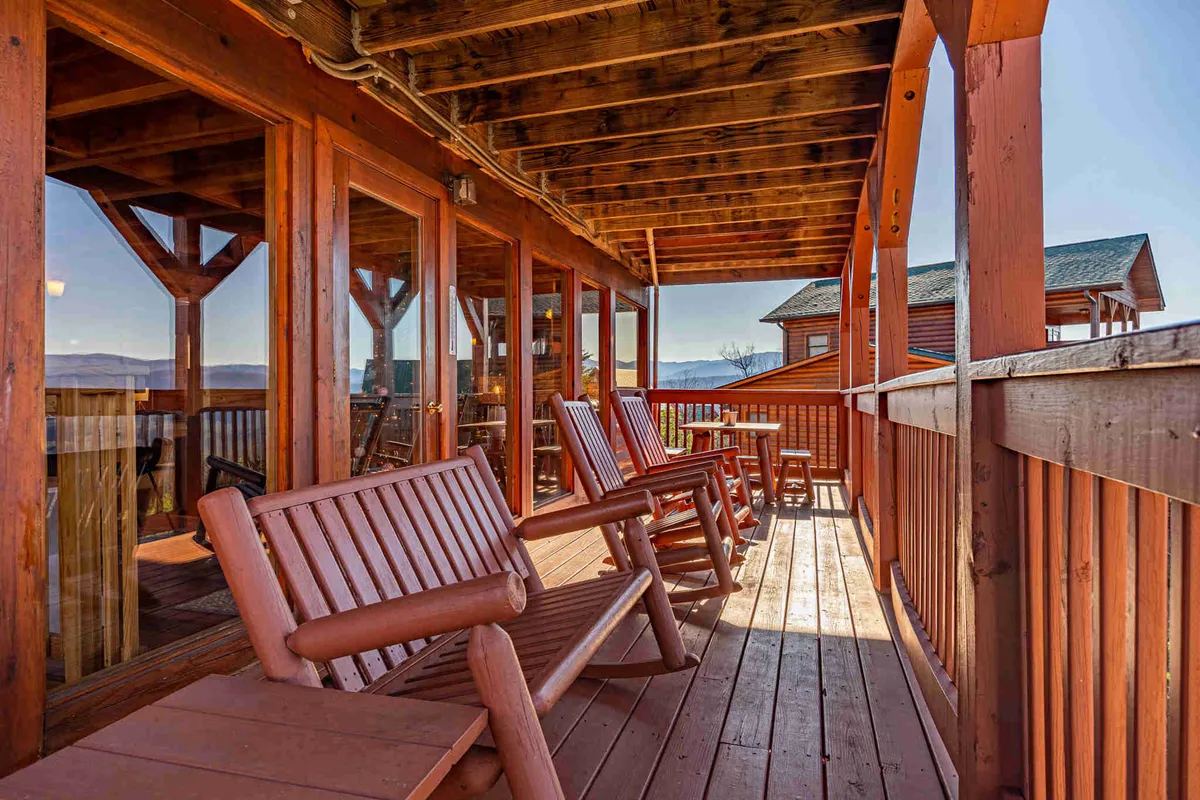 A serene exterior view featuring wooden rocking chairs on a deck with a panoramic mountain vista. It's perfect for relaxing, socializing, and hosting outdoor gatherings, such as barbecues or evening storytelling with friends.